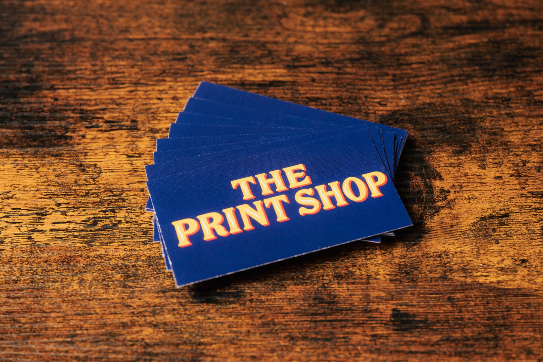 Stack of navy Standard business cards with gold The Print Shop lettering